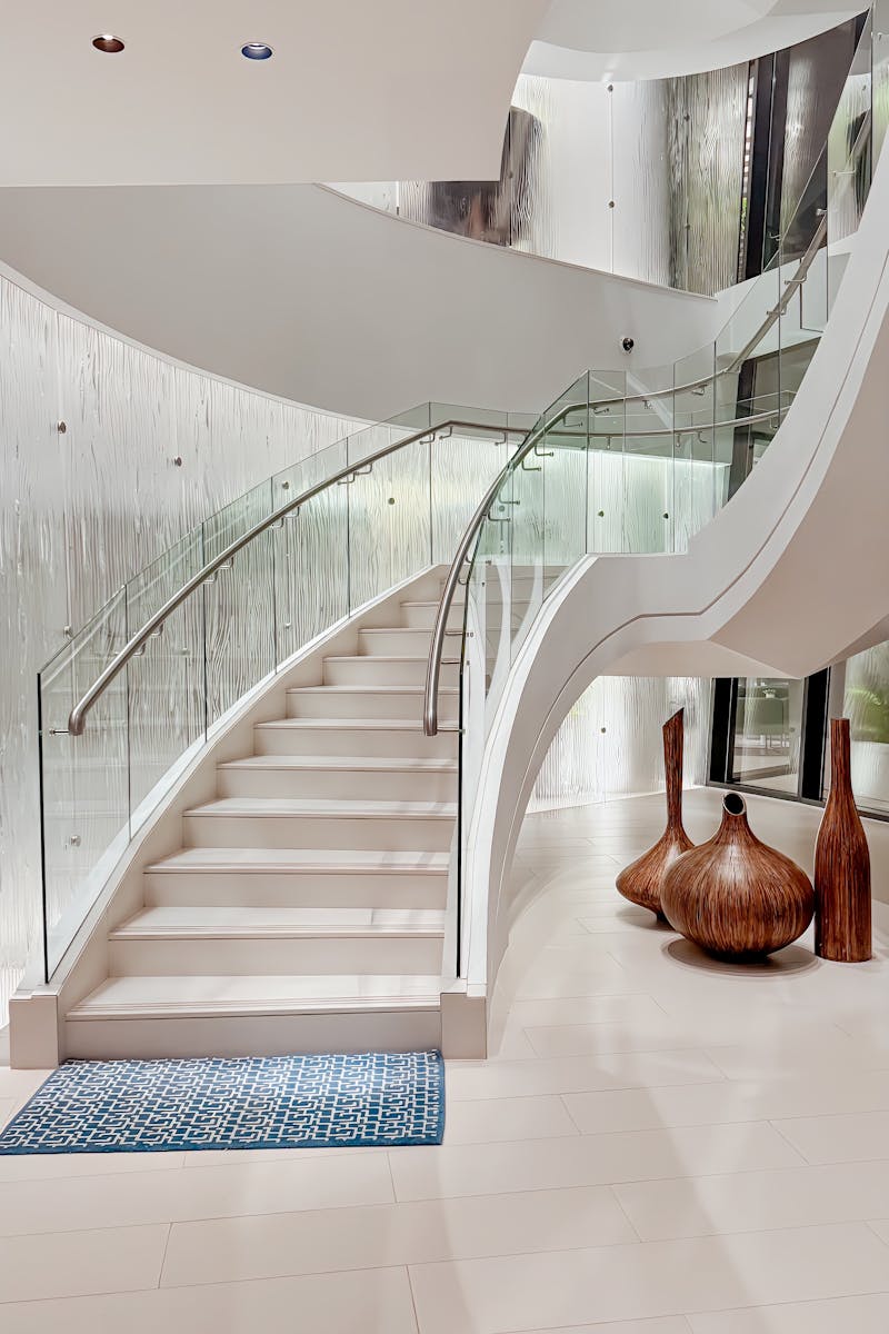 Stunning spiral staircase with glass railing in a luxurious Abu Dhabi home interior.